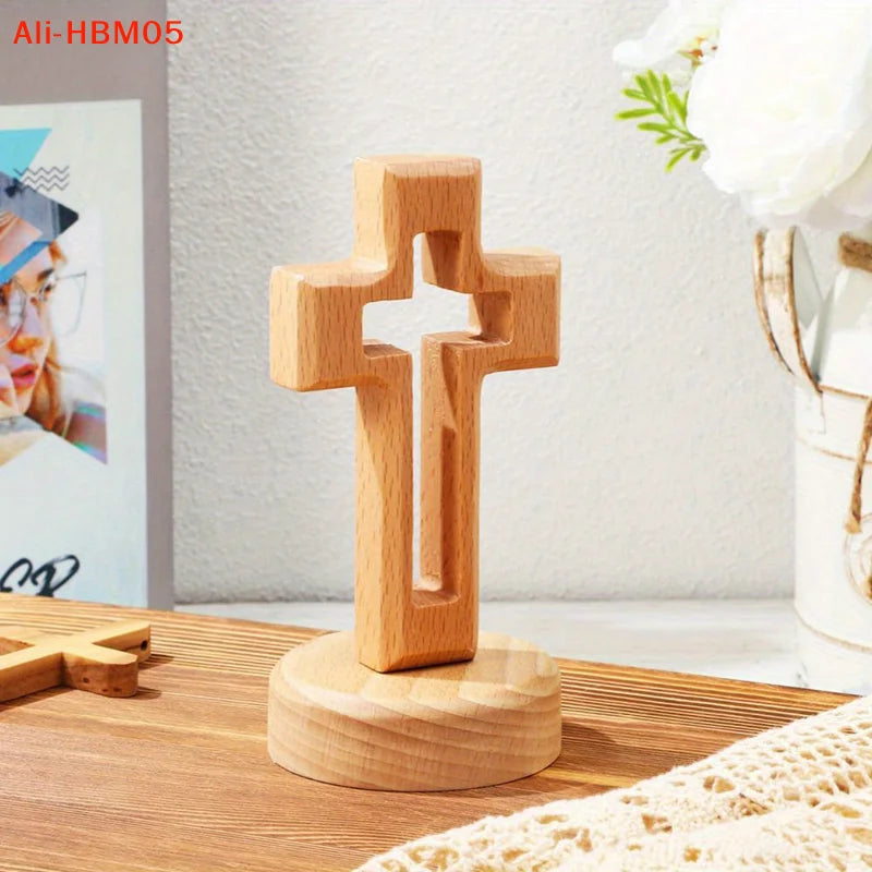 A handcrafted wooden cross standing ornament made of light-colored wood on a wooden surface.