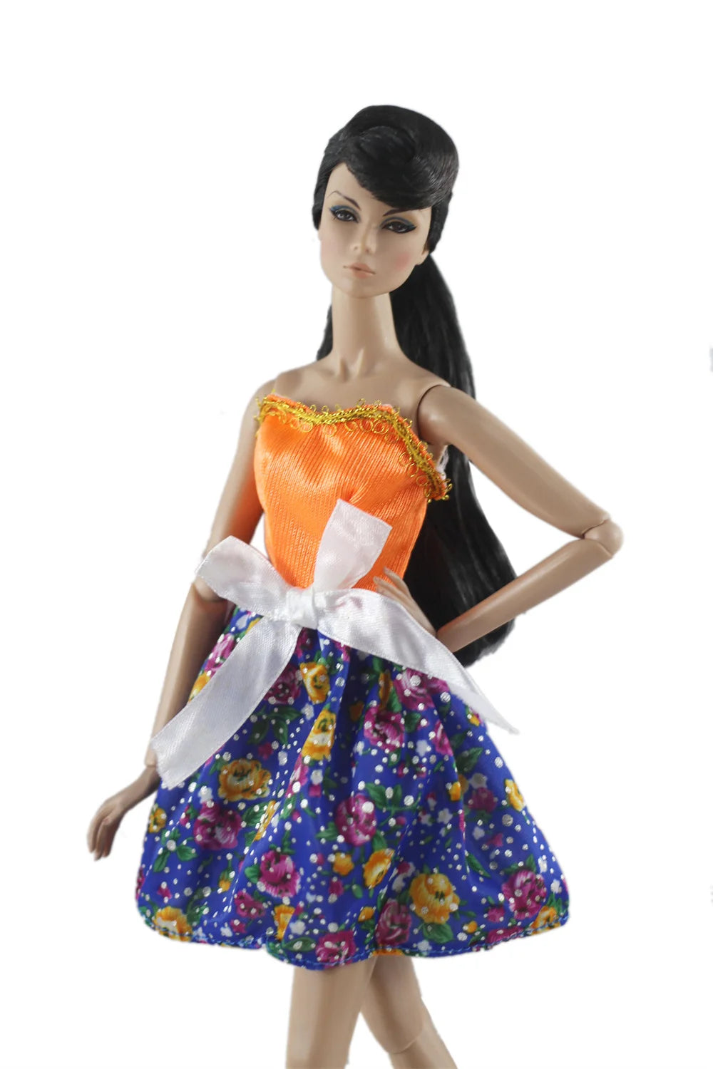 A handmade doll dress gown featuring an orange top and a blue floral skirt with a white bow.