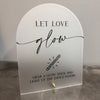 A clear acrylic sign with black script that reads Let Love glow and instructs to grab a glow stick and light up the dance flo