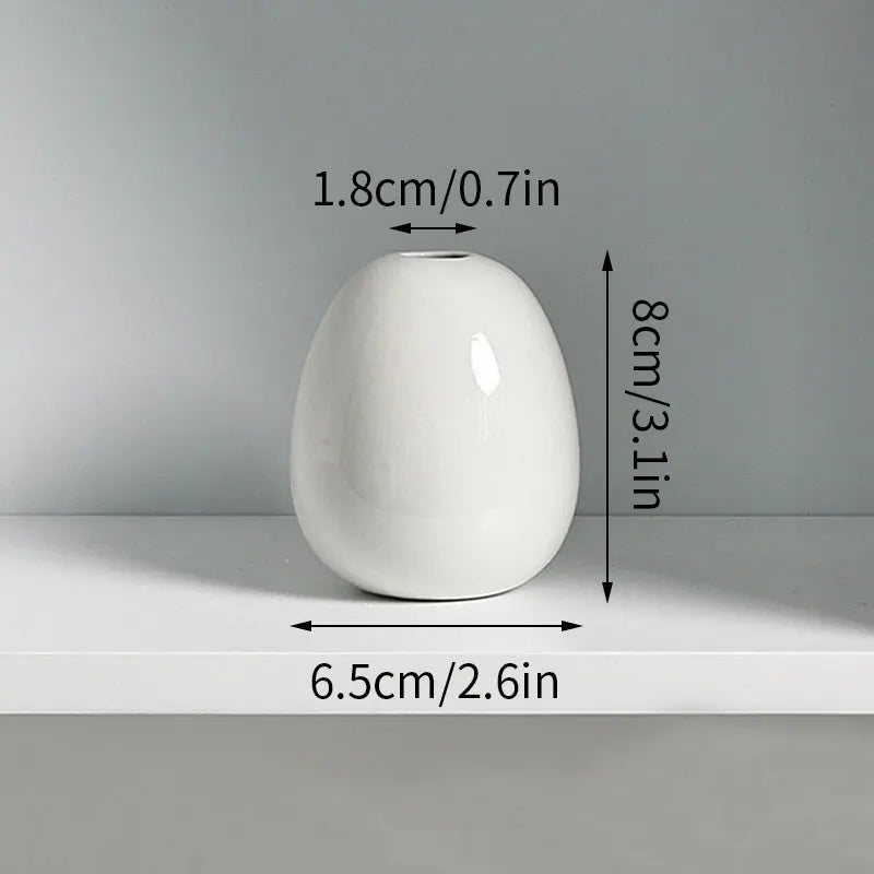 A white ceramic mini vase with a smooth, rounded shape is shown on a shelf.