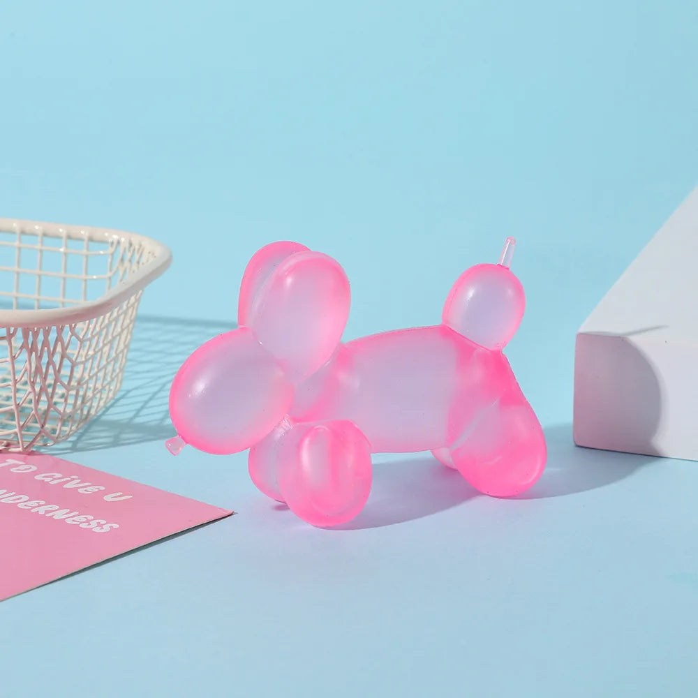 A pink dachshund squishy stress relief toy is shown next to a white wire basket and a white block on a light blue background.