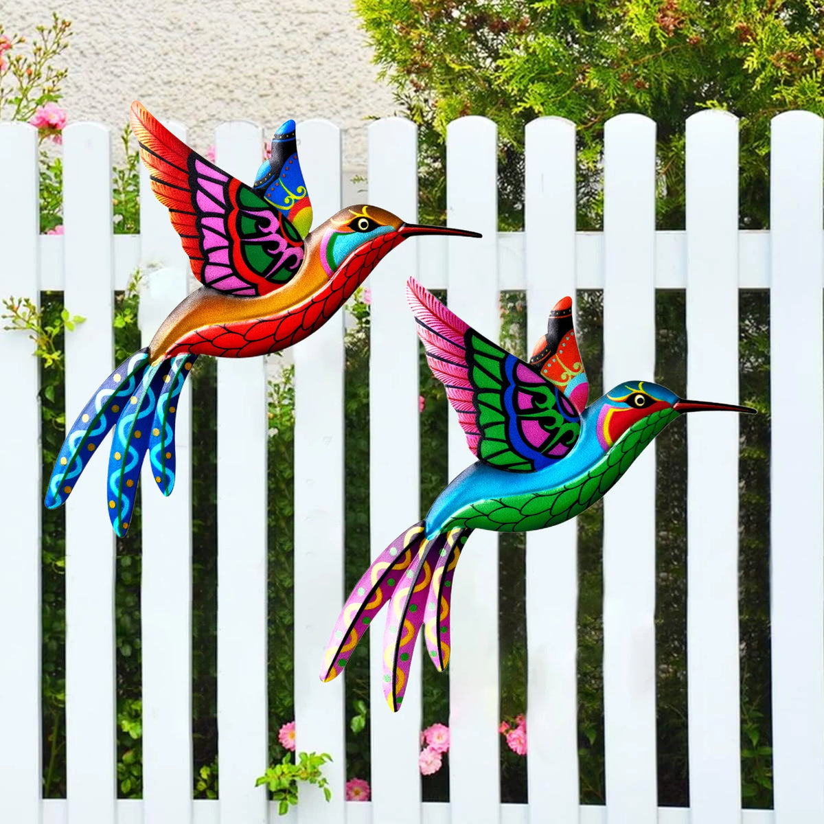 Vibrant metal hummingbird wall art featuring iridescent colors displayed against a white picket fence.