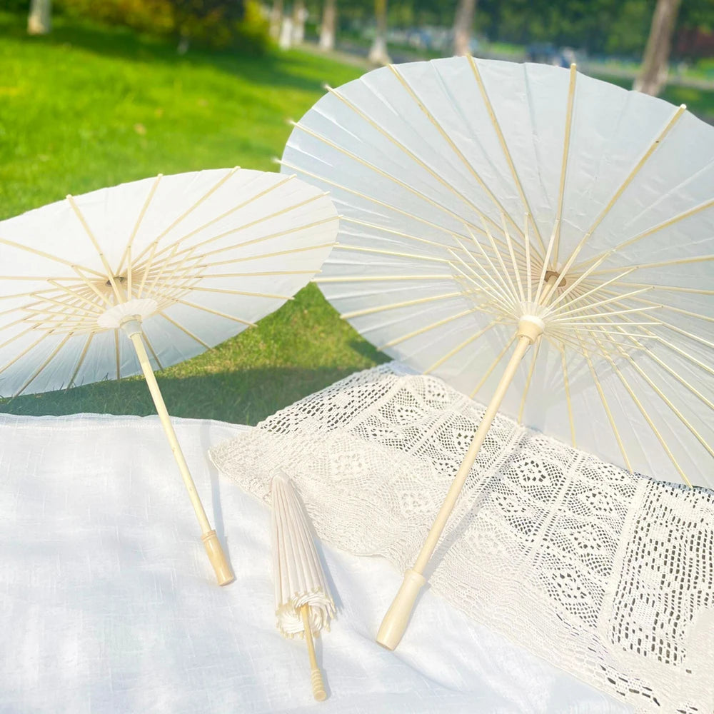 White decorative paper parasols or umbrellas with gold accents resting on a white cloth.