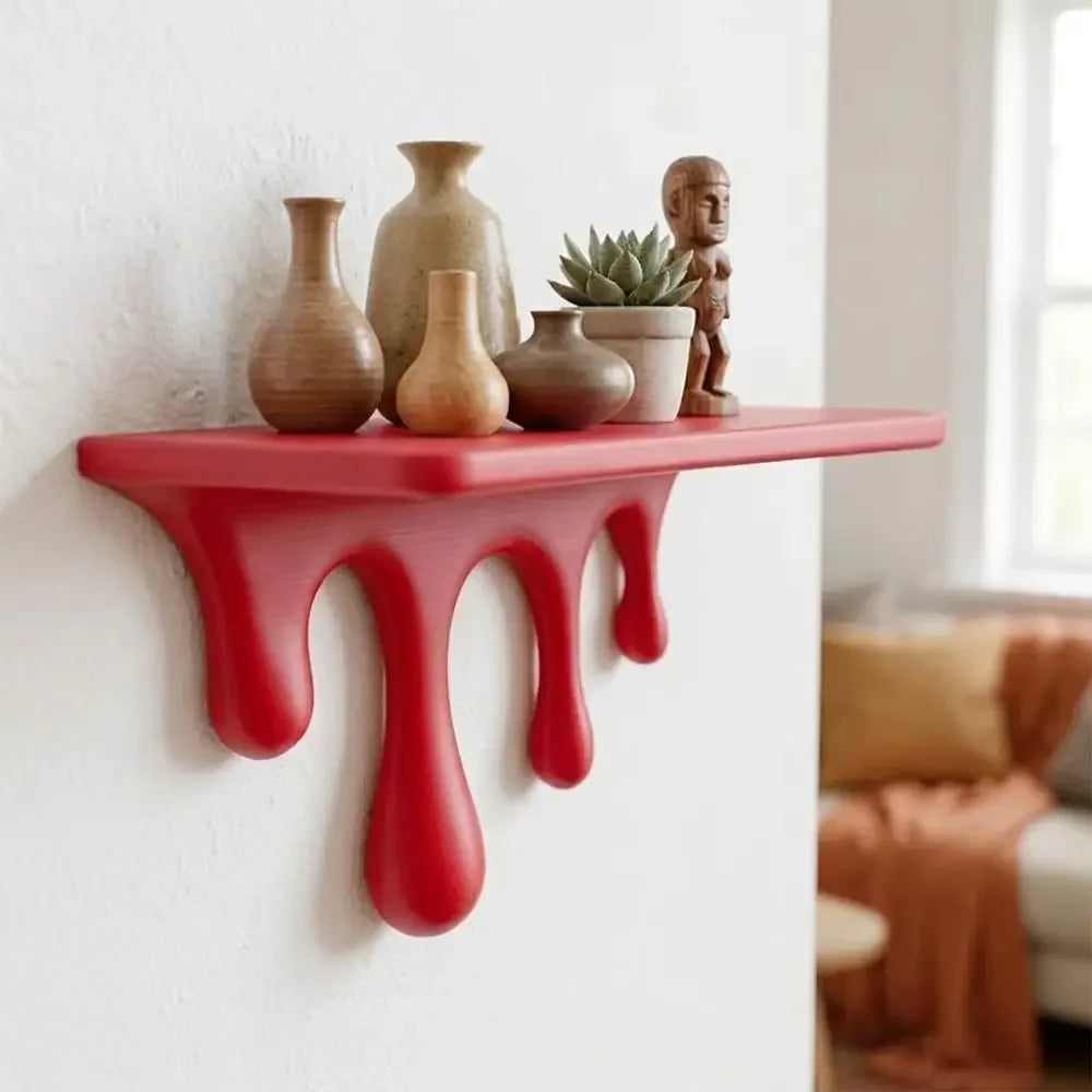 A red drip floating shelf displaying various ceramic vases and a small statue against a white wall.