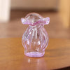 A small, translucent purple glass vase shaped like a stylized flower sits on a wooden surface.