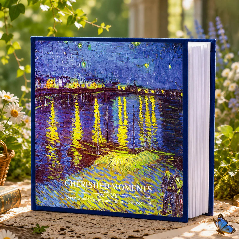 A blue laminated photo album titled Cherished Moments resting on a wooden surface with greenery in the background.