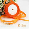 Orange silk satin ribbon rolled on a spool with a white core