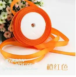 Orange silk satin ribbon rolled on a spool with a white core