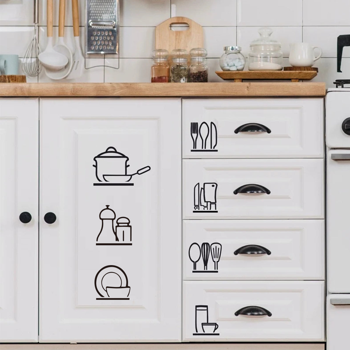 White kitchen cabinet doors featuring black line drawings of various cooking utensils and tableware.