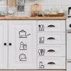 A set of black line art stickers depicting various kitchen utensils and cookware on a white cabinet door.