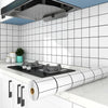 A white kitchen wall featuring black subway tiles and a stainless steel range hood above a countertop with a white roll-up dr