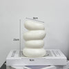 A white, textured plastic decorative vase with a serpentine shape is shown next to a measuring scale.