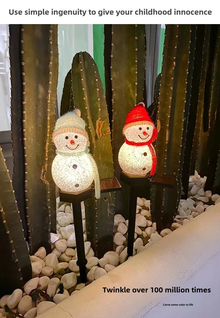 A festive outdoor display featuring three solar-powered Christmas snowman lights in a desert garden setting.