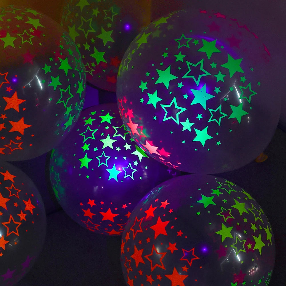 Nahaufnahme von leuchtstoffstift-Latexballons mit neongrünen und pinken Sternen vor dunklem Hintergrund