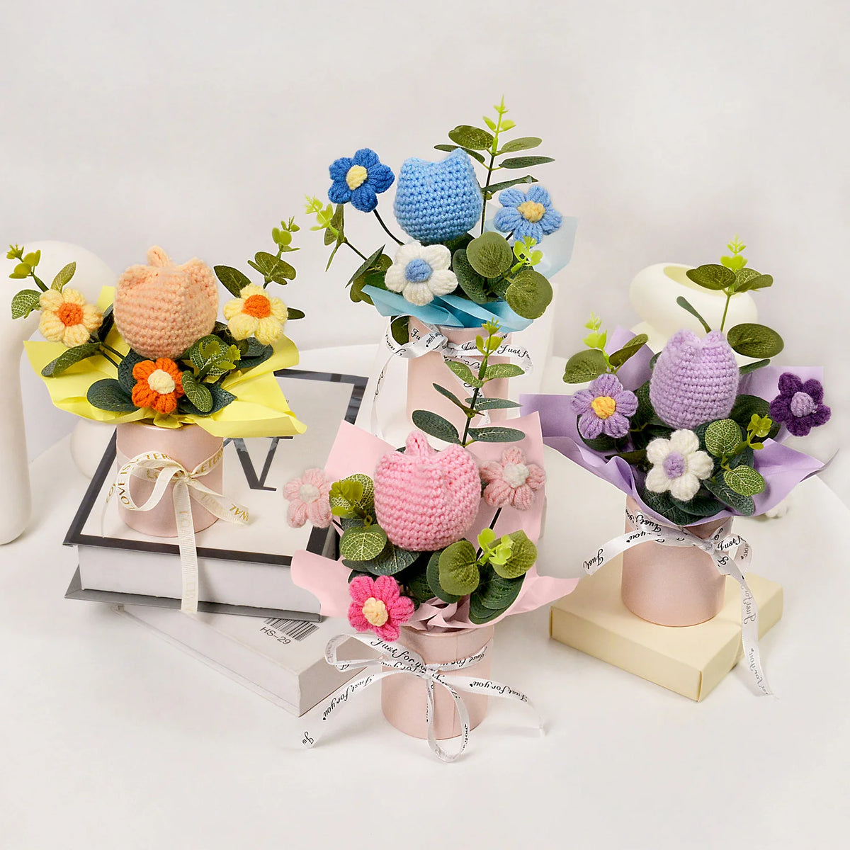 A colorful bouquet of handmade crochet tulips in various shades of blue, purple, and yellow arranged in decorative pots.