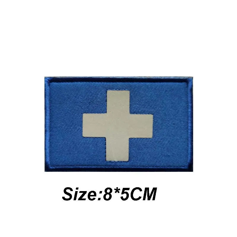 A blue fabric patch with a white cross design, measuring 8 by 5 centimeters.
