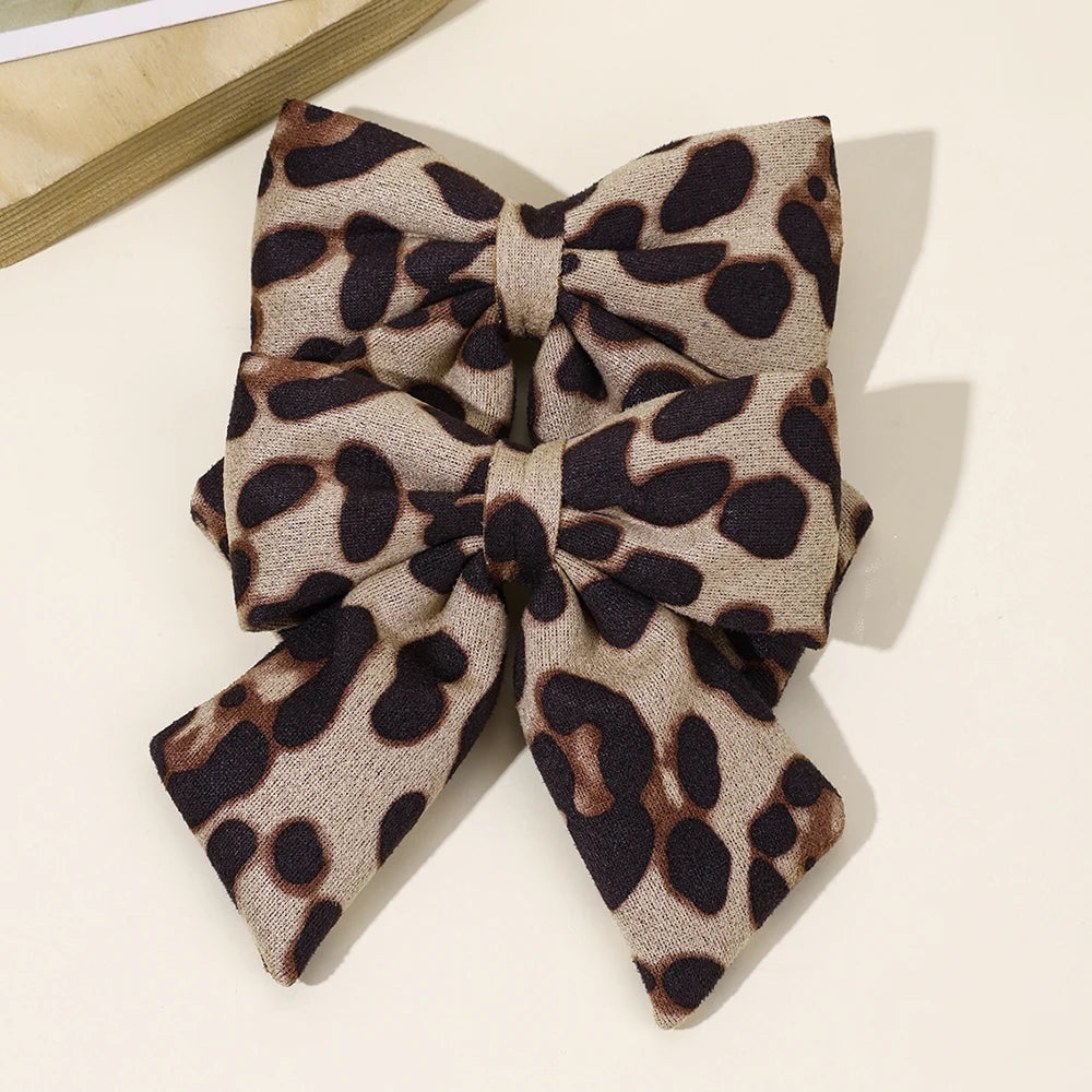 Une paire de pinces à cheveux en velours à imprimé léopard, motif beige et noir.