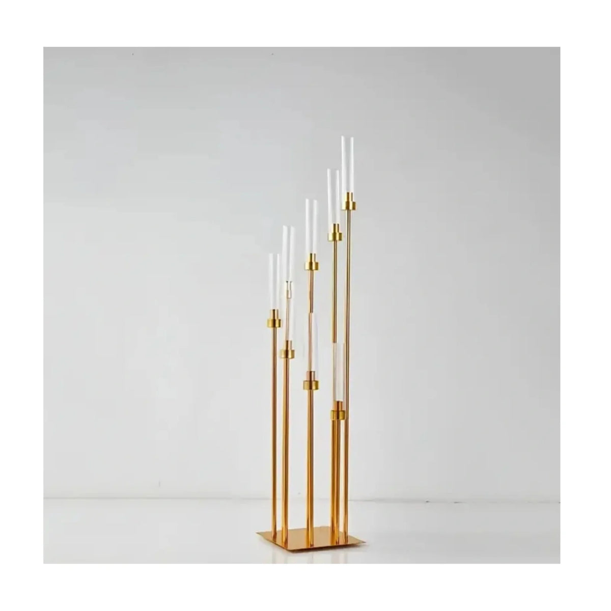 Elegant gold metal candle holders with slender white candles displayed against a white background.