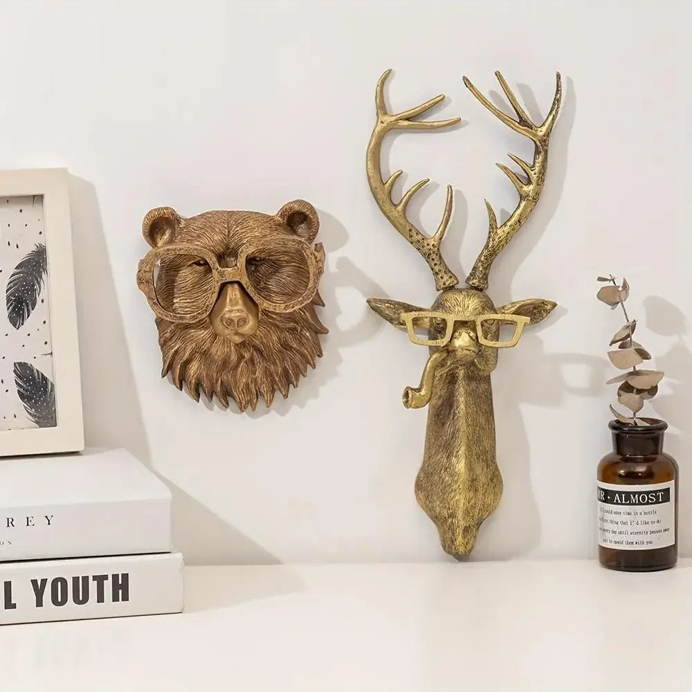 A brass deer head storage hook wall decor featuring antlers and glasses mounted on a white wall.
