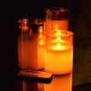 Three glass pillar candles glowing warmly in a dark setting, with a remote timer visible.