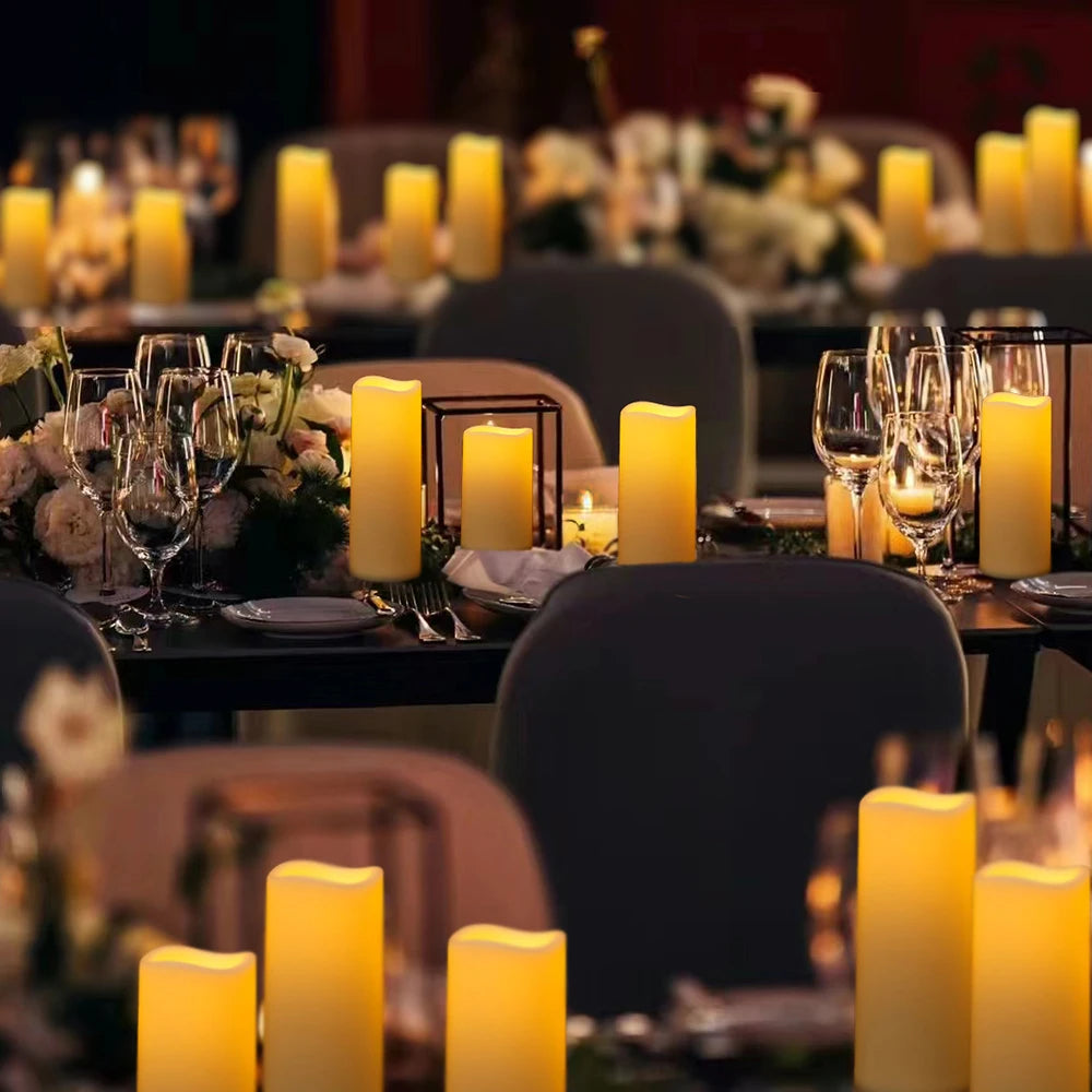 A close-up of a dark table decorated with glowing yellow LED candles and floral arrangements for an event.