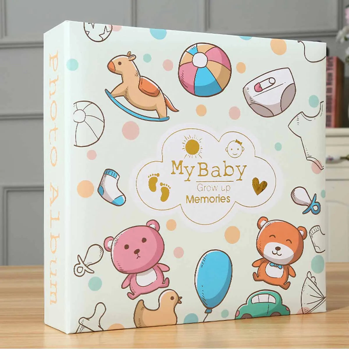 A white photo album titled My Baby Grow Up Memories featuring illustrations of baby items like a rocking horse, pacifier, and