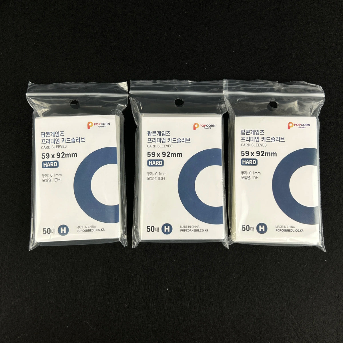 Three packs of clear protective card sleeves labeled as POPCORN brand with dimensions 59 x 92mm and quantity 50