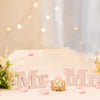 A bridal centerpiece featuring a bouquet of yellow and peach roses and pink petals on a white table.