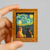 A framed print featuring a Van Gogh style starry sky with cats in a wooden frame.