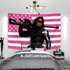 A pink American flag tapestry wall hanging displayed above a bed.