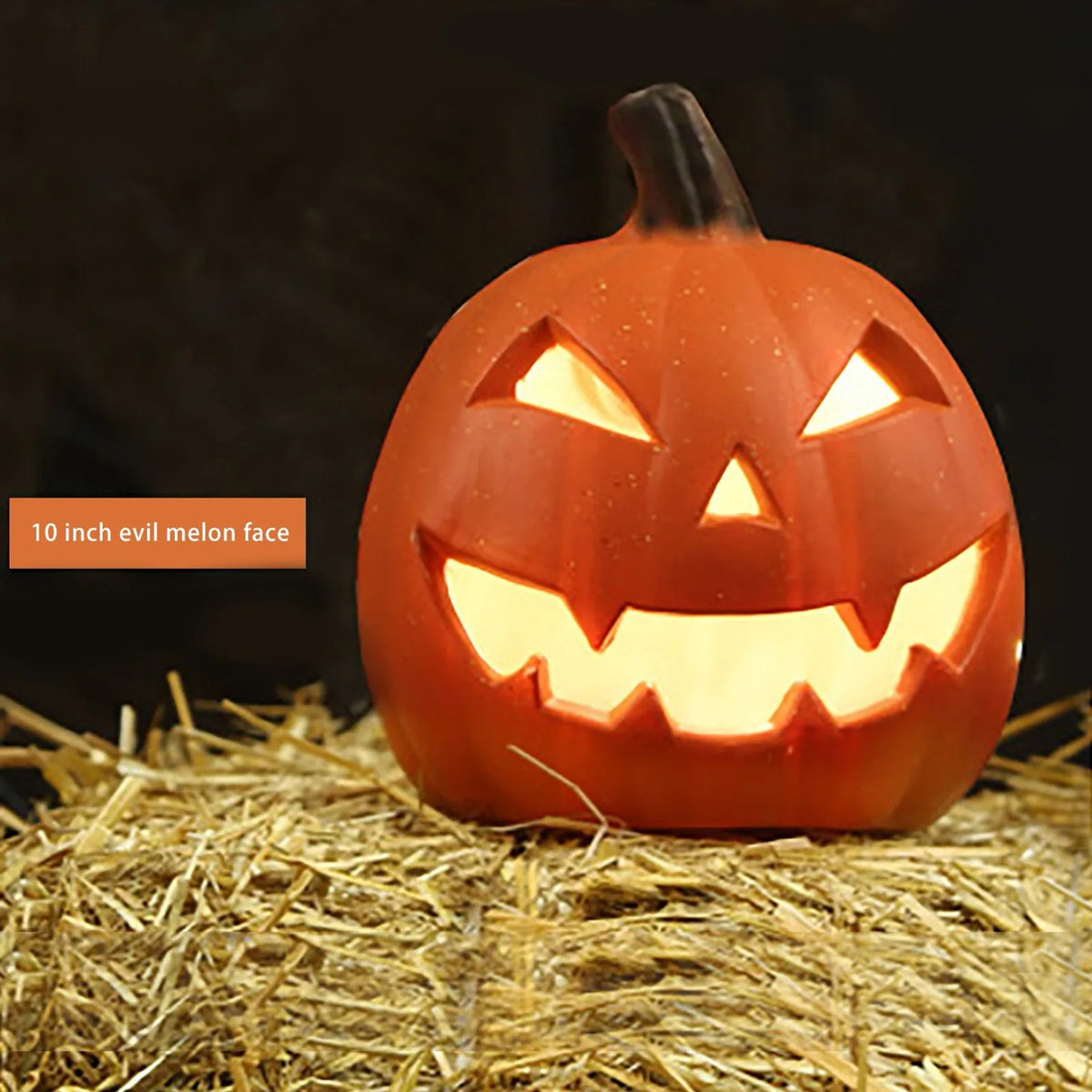 Linterna de calabaza de cerámica naranja con cara amenazadora, sobre paja.