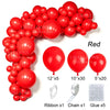 A collection of red latex balloons, ribbons, chains, and glue for party decor.