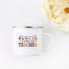 A white enamel mug with a floral design and the word TEACHER printed on it, set against a white background.