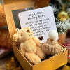 A fluffy light brown worry bear plush toy resting in a gold gift box with an encouraging card.