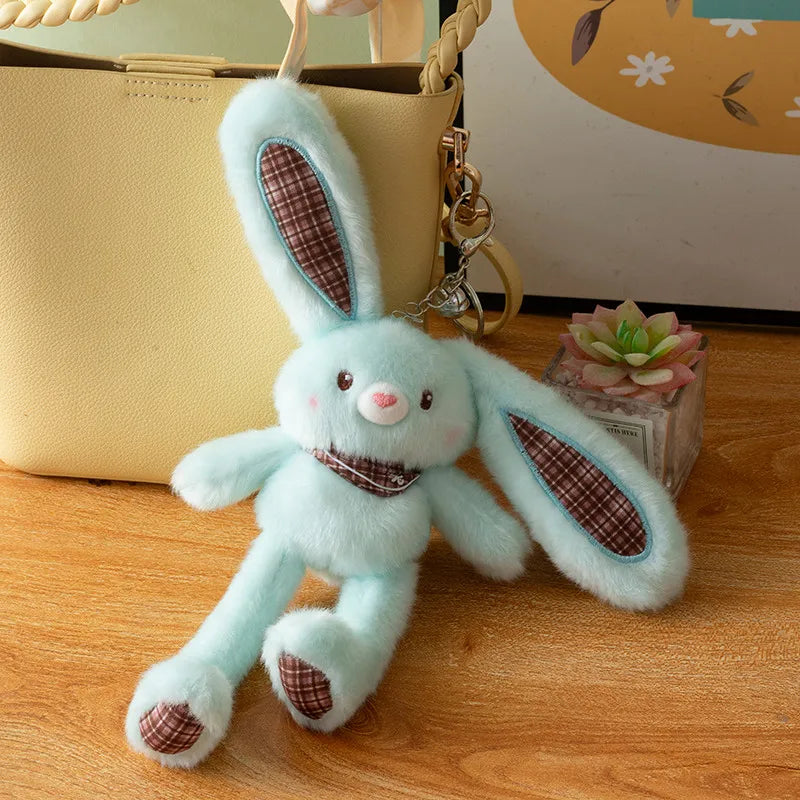 A light blue giant kawaii rabbit plush toy with brown accents sitting on a wooden surface next to a beige bag.