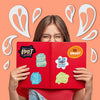 A person holds a red notebook with inspirational quotes written on the pages against an orange background.