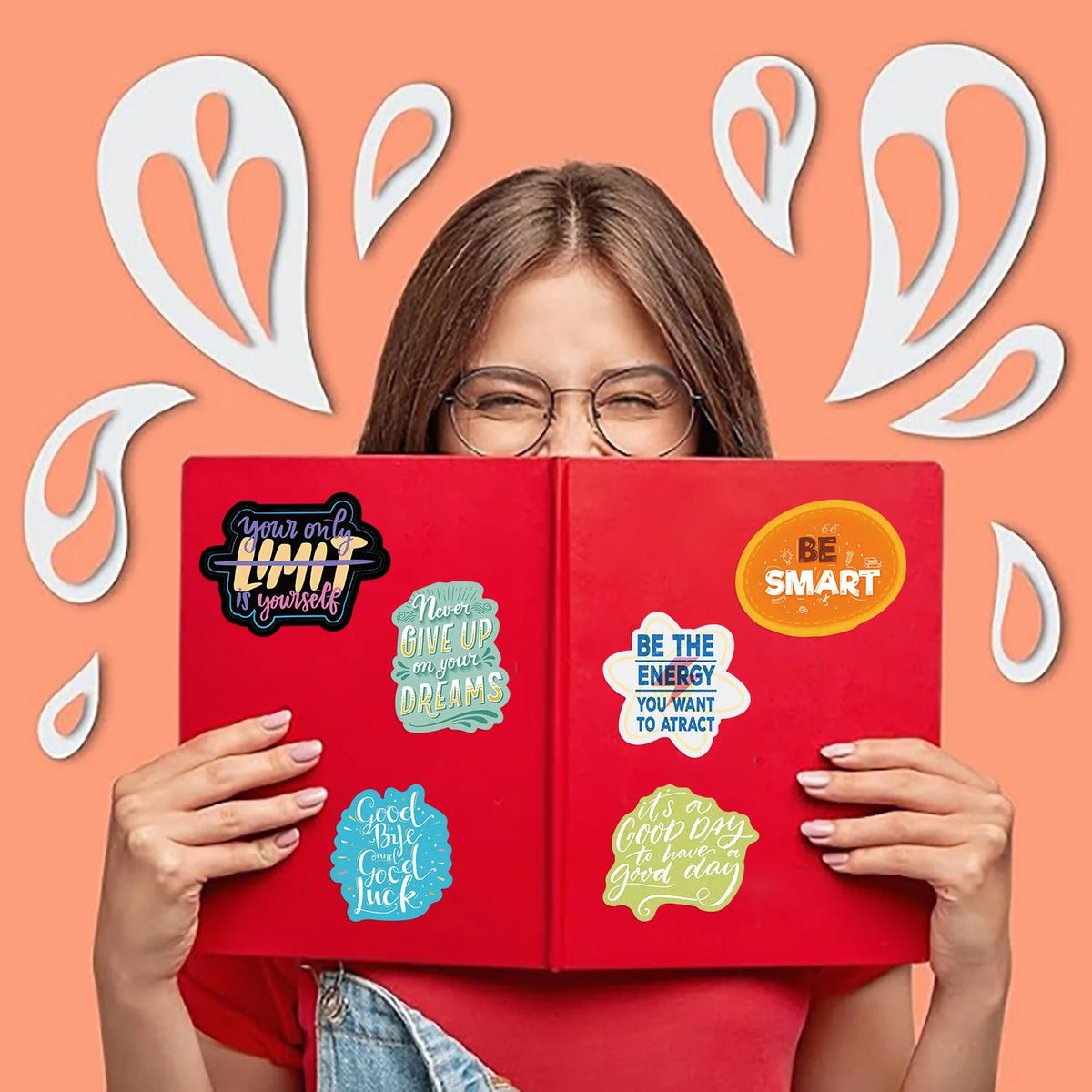 A person holds a red notebook with inspirational quotes written on the pages against an orange background.