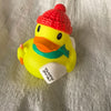 A yellow rubber duck toy with an orange beak and green accents, resting on a silver textured surface.