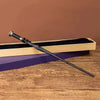 A dark metal magic wand rests diagonally across a wooden box with a purple lining on a rustic table.