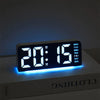 Reloj de alarma LED digital mostrando las 20:15 en una superficie blanca con luz ambiental azul.