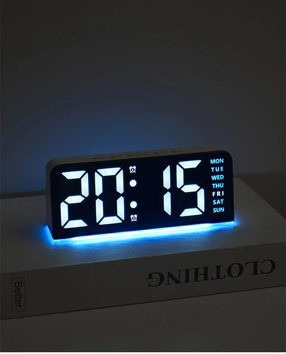 Reloj de alarma LED digital mostrando las 20:15 en una superficie blanca con luz ambiental azul.