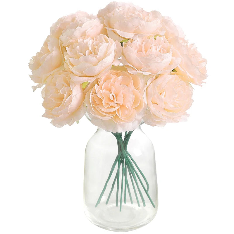 A bouquet of six light pink artificial peony flowers arranged in a clear glass vase.