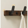 A dark walnut wood coat rack with eight hooks and a storage shelf mounted on a light wall.