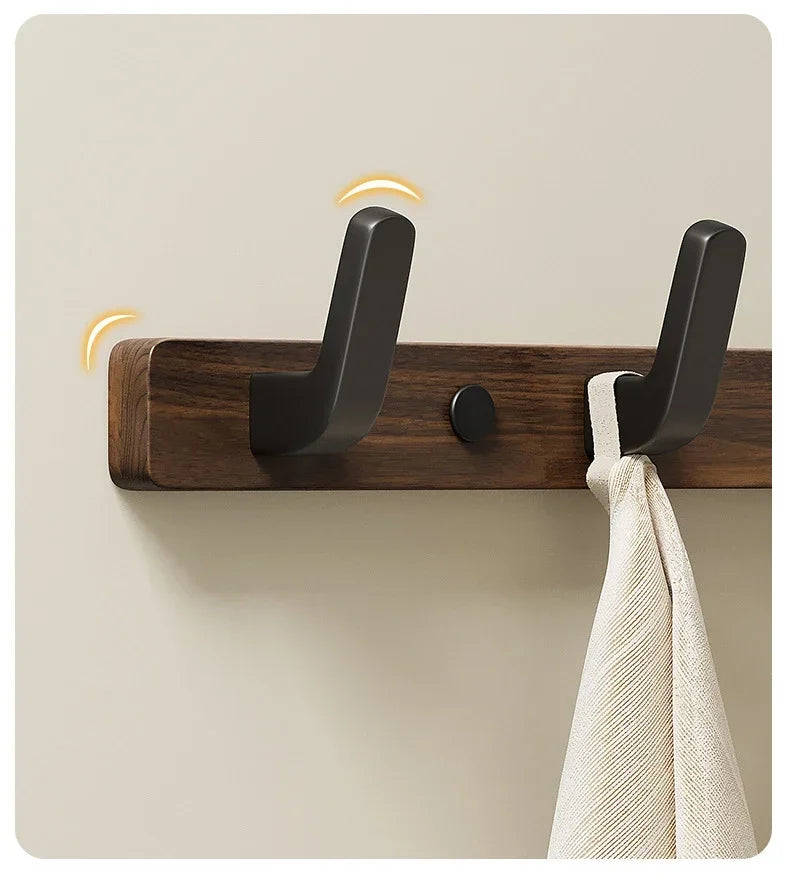 A dark walnut wood coat rack with eight hooks and a storage shelf mounted on a light wall.