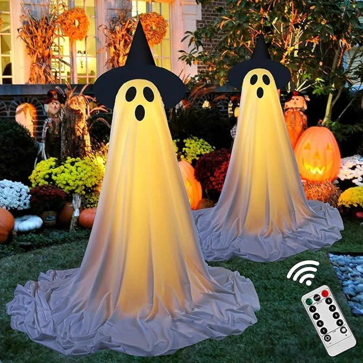 A large, glowing ghost decoration with a black hat and white face is displayed outdoors in a garden setting.