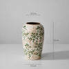 A rustic ceramic milk pitcher with a pale cream glaze and pastoral floral design, shown against a white background.