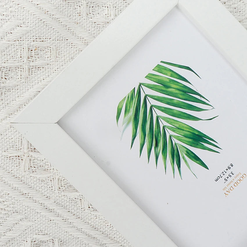 A white photo frame displaying a green palm leaf watercolor illustration on a white background.