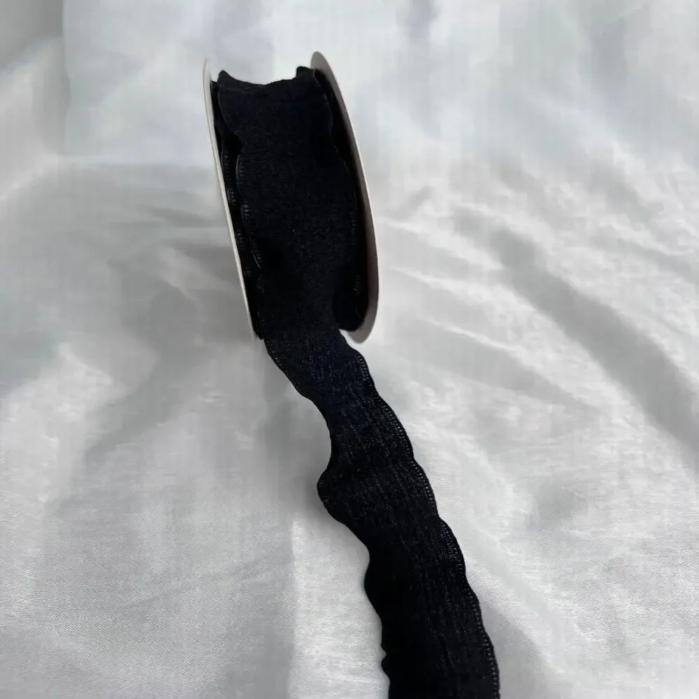 A close-up view of a black decorative fishtail yarn ribbon.