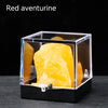 A clear box displays a yellow-orange red aventurine crystal rough stone specimen.