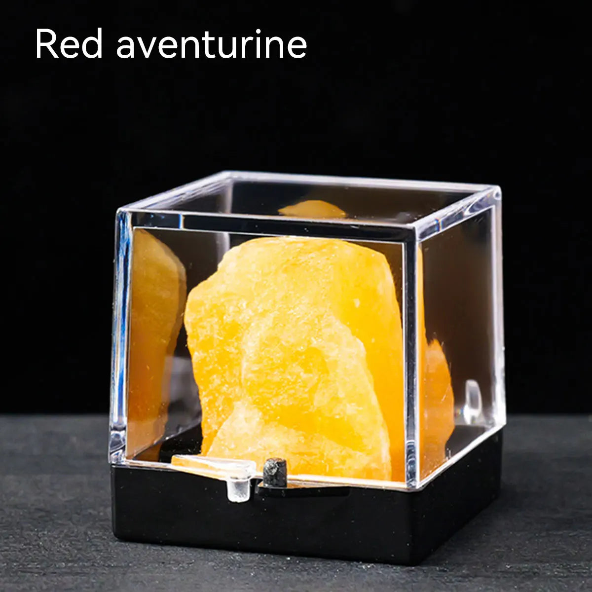 A clear box displays a yellow-orange red aventurine crystal rough stone specimen.